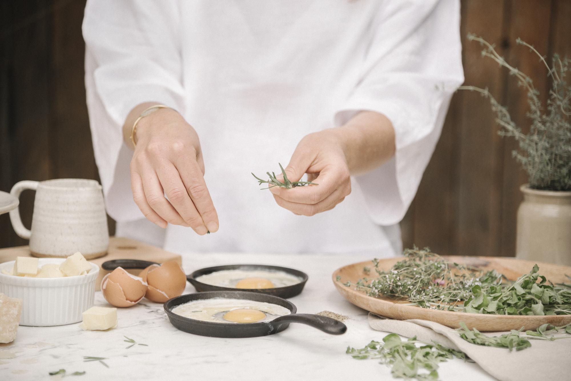 Chef arranging herbs in a sunlit kitchen